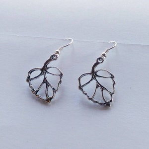 May include: A pair of silver leaf-shaped dangle earrings. The earrings are made of metal and have a delicate, intricate design.