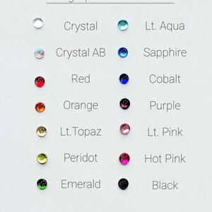 May include: A chart showing 12 different colors of rhinestones with their names. The colors are: Crystal, Lt. Aqua, Crystal AB, Sapphire, Red, Cobalt, Orange, Purple, Lt. Topaz, Lt. Pink, Peridot, Hot Pink, Emerald, and Black.