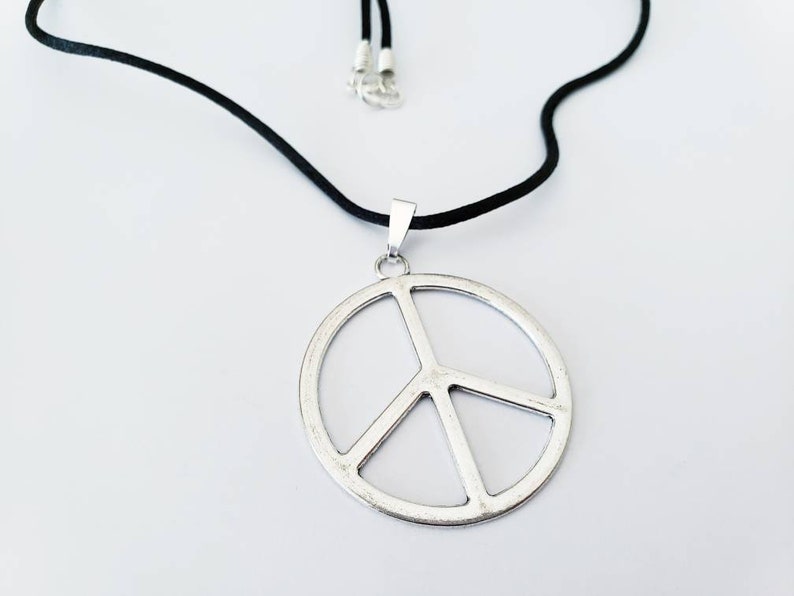 May include: A silver peace sign pendant necklace on a black cord.