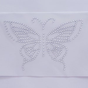 May include: A white fabric patch with a clear rhinestone butterfly design.
