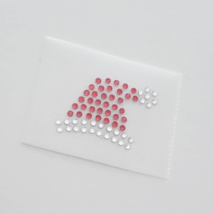 May include: A white fabric patch with a red and clear rhinestone design of a Santa hat.