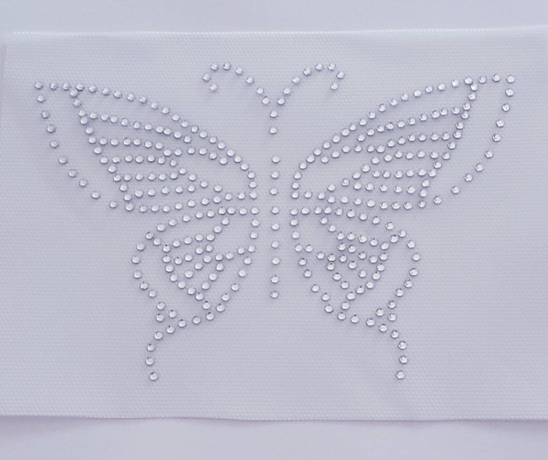 May include: A white fabric patch with a silver rhinestone butterfly design.