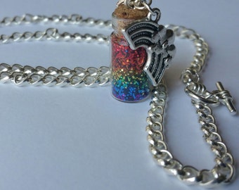 Könnte beinhalten: Eine silberne Kettenkette mit einer kleinen Glasflasche, gefüllt mit Regenbogen-Glitzer. Die Flasche hat einen Korkverschluss und einen silbernen Anhänger in Form eines Flügels.