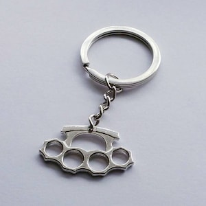 May include: A silver key chain with a silver key ring and a silver knuckle duster charm.