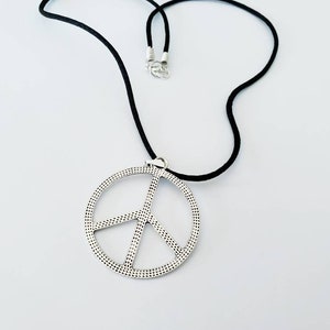 May include: A silver peace sign pendant necklace with a black cord.