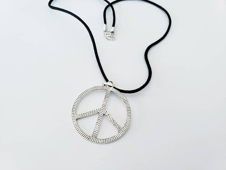 May include: A silver peace sign pendant necklace with a black cord.