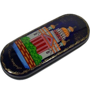 May include: A blue and gold painted glasses case with a depiction of a church building and the text "Санкт-Петербург".