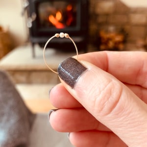 May include: A delicate gold ring with three small white beads.
