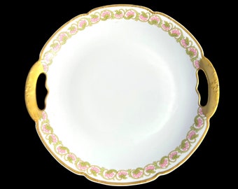 May include: A white porcelain serving platter with gold trim and a pink and green floral design. The platter has two gold handles.