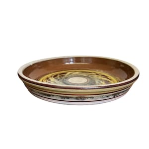 May include: A brown ceramic dish with a white and yellow swirl design. The dish has a wide rim with multiple brown, white, and yellow stripes.