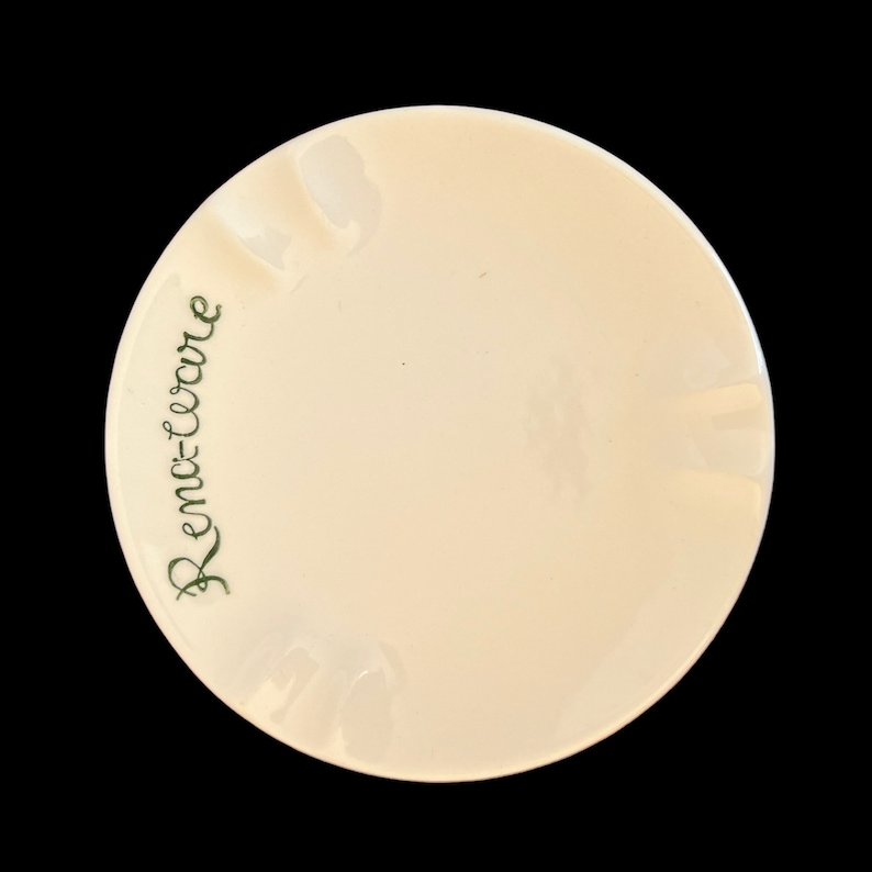 May include: White ceramic ashtray with a green inscription that reads "Remco-Ware".