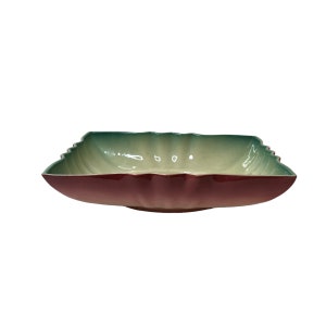 May include: A square ceramic serving bowl with a green and burgundy glaze. The bowl has a scalloped edge and a slightly rounded bottom.