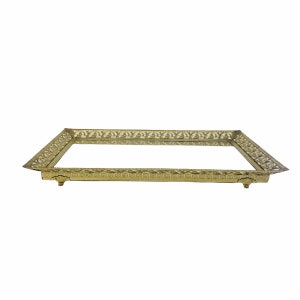 May include: A gold-coloured metal tray with a mirrored surface and an ornate design around the edge. The tray has four small feet.