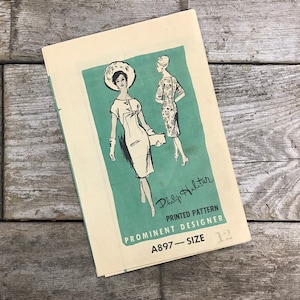 May include: A vintage sewing pattern for a dress, featuring two women in dresses. The pattern is by Philip Hulitar, a prominent designer. The pattern number is A897 and the size is 12.