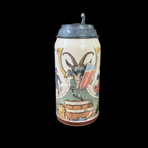 May include: A vintage beer stein with a hinged metal lid. The ceramic body features a colorful illustration of a goat, a glass of red liquid, and figures in period clothing. The stein is cream-colored with a brown base.