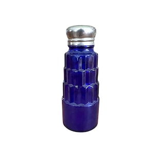 May include: A cobalt blue glass salt shaker with a silver-colored metal lid. The body of the shaker has a geometric, faceted design. The salt shaker is a vintage item.