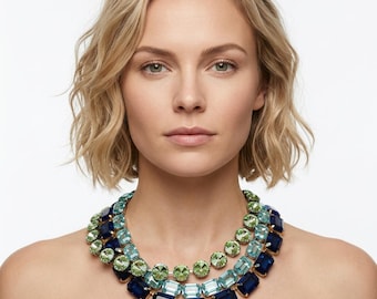 Puede incluir: Un collar llamativo de varias hileras con tres capas distintas de cristales facetados. La capa superior consta de cristales redondos de color verde claro, la capa intermedia presenta cristales rectangulares de color azul claro y la capa inferior muestra grandes cristales rectangulares de color azul marino profundo engastados en un marco metálico.