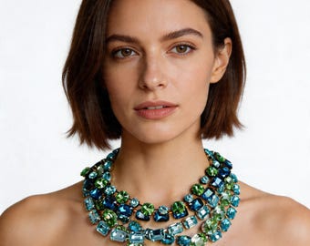 May include: A statement necklace with multiple strands of large, colourful gemstones in shades of blue and green. The necklace features rows of rectangular and oval-shaped stones, creating a striking design. The gemstones are set in a dark metal.