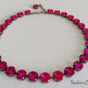 May include: A pink crystal necklace with a silver chain. The necklace is made up of round, faceted crystals.