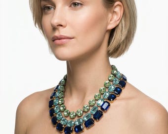 May include: A multi-strand statement necklace featuring three rows of faceted crystals in a gradient of colors. The top row consists of light green stones, the middle row of light blue stones, and the bottom row of deep navy blue rectangular stones.