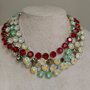 May include: A multi-layered necklace with red, green, and white iridescent crystals. The necklace is made of silver-toned metal and has a cascading design.