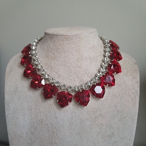 May include: A red crystal necklace with a silver chain and heart-shaped crystals.