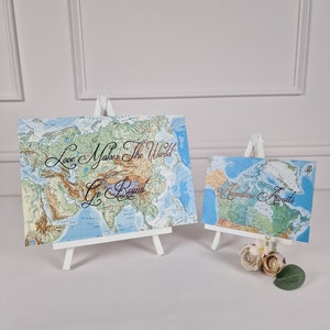 Adventure Awaits, Love makes the world go round handwritten world map sign.