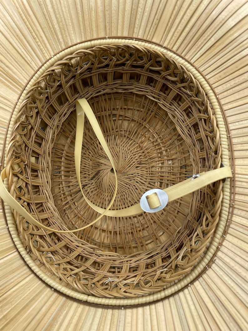 Puede incluir: El interior de un sombrero de paja tejido con una banda tejida marr&oacute;n y una hebilla de metal. El sombrero est&aacute; hecho de materiales naturales y tiene un dise&ntilde;o tradicional.