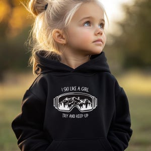 May include: Black hooded sweatshirt with a white graphic of ski goggles and the text "I ski like a girl try and keep up".