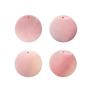 May include: Four round, pink pendants with a glossy finish. Each pendant has a small hole at the top for stringing. The pendants vary slightly in shade, ranging from light to deeper pink.