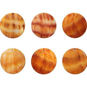May include: Six round, polished shell pendants in shades of orange and brown. Each pendant has a natural, swirling pattern and a small hole at the top for stringing. The pendants are ideal for jewelry making or craft projects.