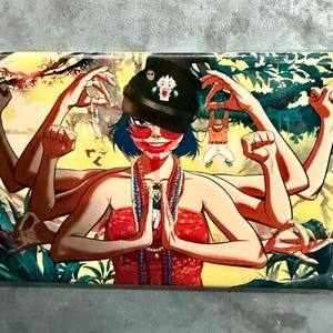 May include: Rectangular art print featuring a multi-armed figure with blue hair, red lipstick, and sunglasses. The figure wears a red top and a black beanie with a cartoon face. The background is a yellow and green landscape.