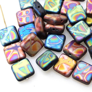 May include: A pile of iridescent square glass beads with a variety of colours and patterns. The beads are approximately 1 cm in size and have a glossy finish.
