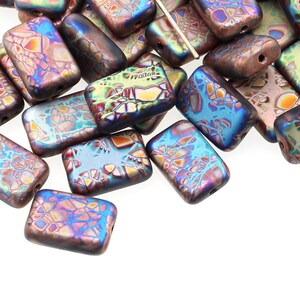 May include: A pile of iridescent glass beads in shades of blue, green, and brown. The beads are rectangular and have a textured surface.