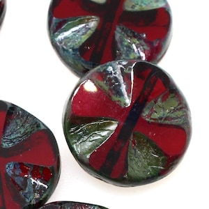 May include: Red and green glass beads with a cross design. The beads are round and have a slightly irregular shape.