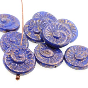 May include: A group of blue and gold glass beads with a spiral design. The beads are round and have a textured surface.
