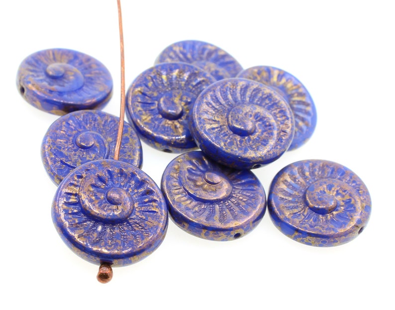 May include: A group of blue and gold glass beads with a spiral design. The beads are round and have a textured surface.