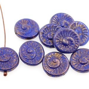 May include: A collection of blue and gold glass beads with a spiral design. The beads are round and have a textured surface.