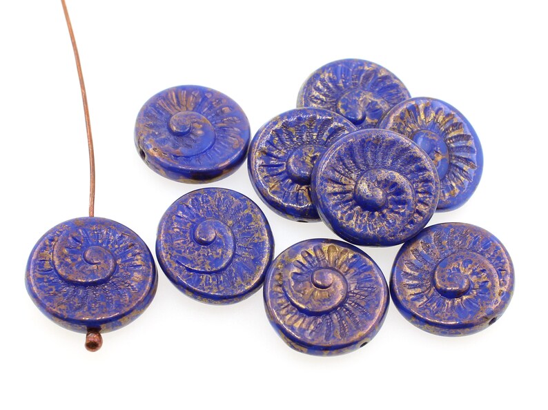 May include: A collection of blue and gold glass beads with a spiral design. The beads are round and have a textured surface.