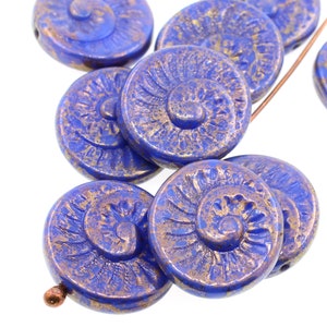 May include: A group of blue glass beads with a gold metallic finish. The beads are round and have a spiral design.