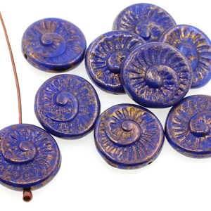 May include: A group of blue glass beads with a gold swirl design. The beads are round and have a slightly textured surface.