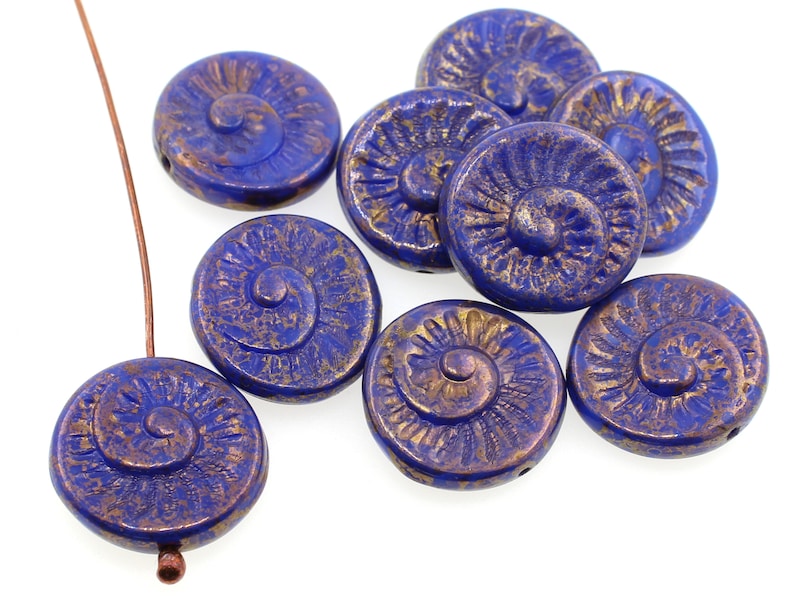 May include: A group of blue glass beads with a gold swirl design. The beads are round and have a slightly textured surface.