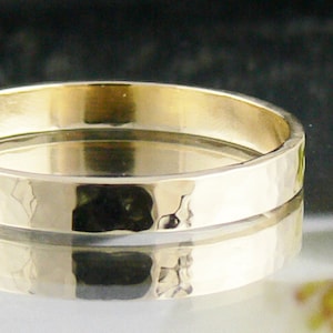 May include: A simple gold band ring with a hammered texture.