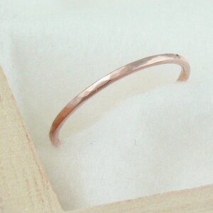 May include: A thin, hammered rose gold band ring.