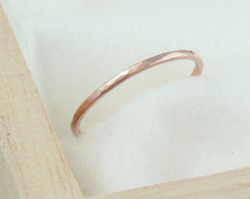 May include: A thin, hammered rose gold band ring.