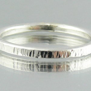 May include: A silver ring with a hammered texture. The ring is simple and elegant.