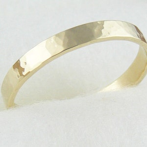 May include: A simple gold band ring with a hammered finish.