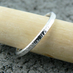May include: A thin silver band ring with a hammered texture.