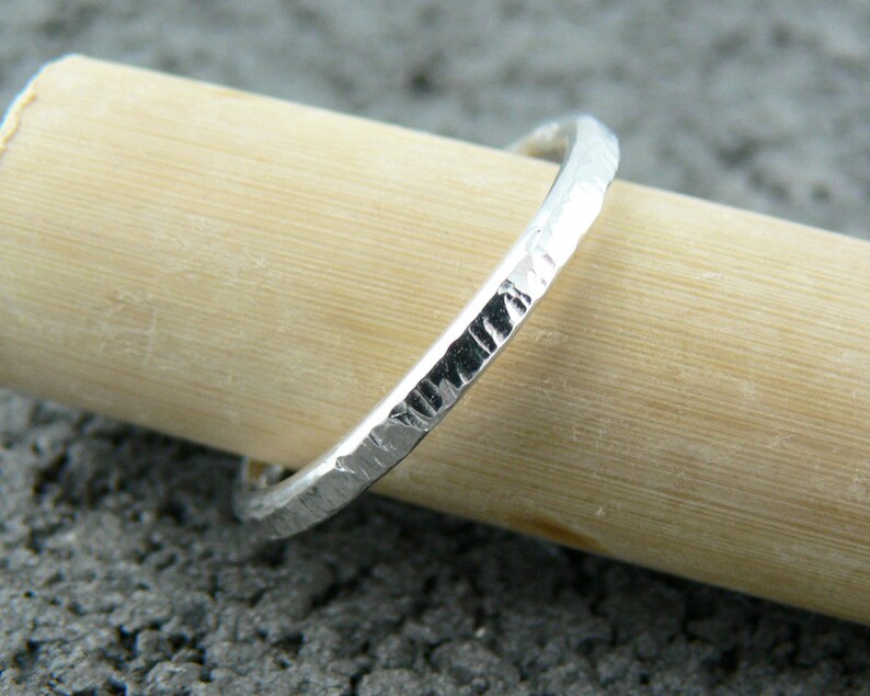 May include: A thin silver band ring with a hammered texture.