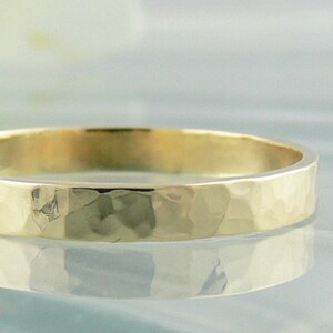May include: A simple gold band ring with a hammered texture.